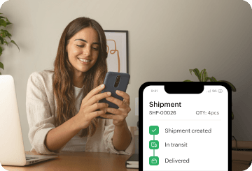 A woman smiles while using the Zoho Inventory mobile order tracking app.